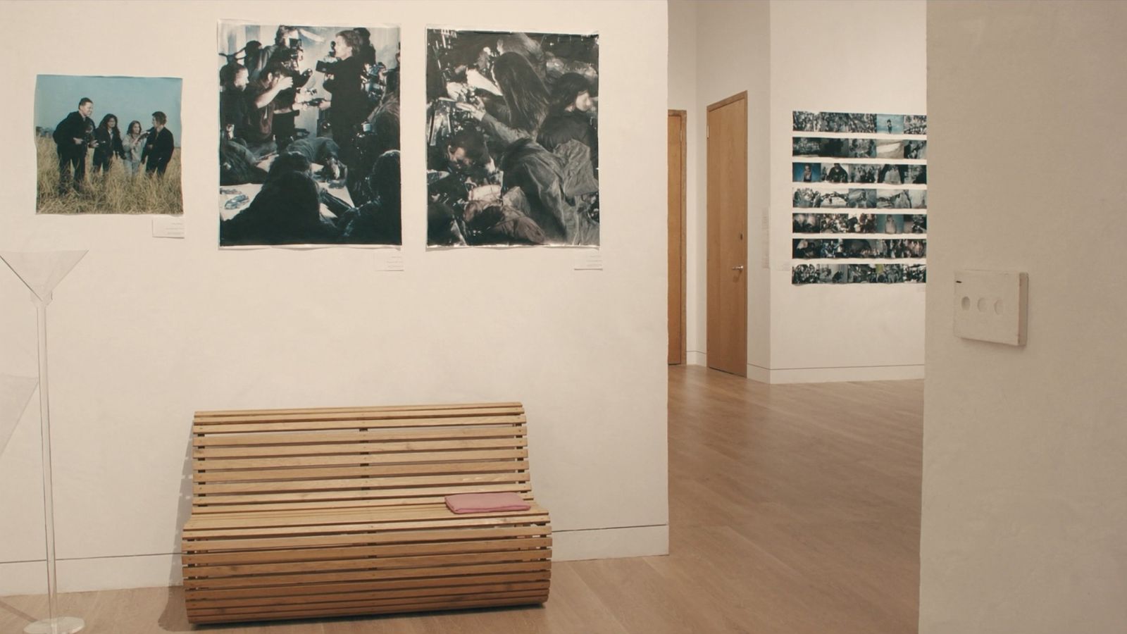 A gallery hall lined with framed prints and lit display cases, a bench down the center, soft warm light on the walls.